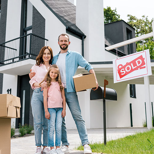 Family standing in front of house with sold sign